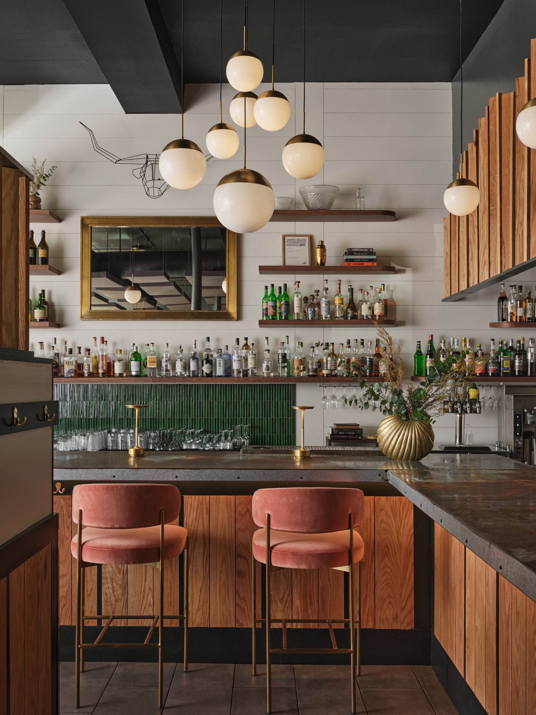The bar at Hunt & Alpine, with brass globe pendants, green tile and pink velvet stools