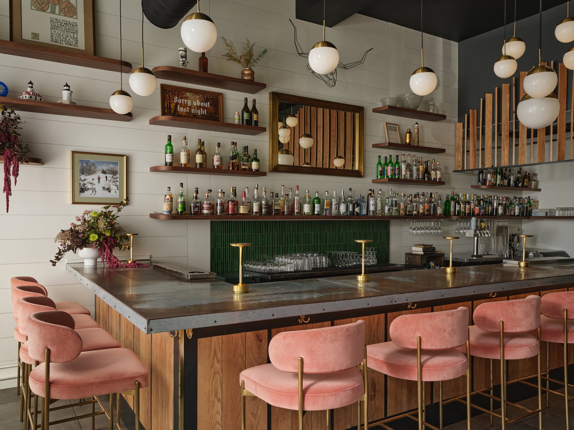 The bar at Hunt & Alpine, with pink velvet stools and brass globe pendants